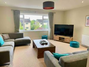 a living room with couches and a flat screen tv at Modern and cosy 4 bedroom home in the Mendip Hills, North Somerset in Axbridge