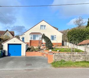 a house with a blue garage in front of it at Modern and cosy 4 bedroom home in the Mendip Hills, North Somerset in Axbridge