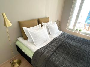 um quarto com uma cama com almofadas brancas e um candeeiro em Tilava yksiö 35,5 m2 merenrannalla em Helsinque