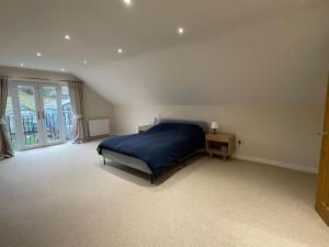 a bedroom with a blue bed and a window at Modern and cosy 4 bedroom home in the Mendip Hills, North Somerset in Axbridge