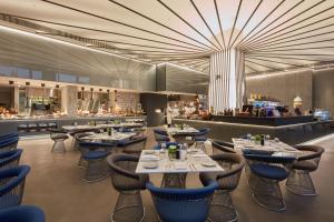 ein Restaurant mit Tischen und Stühlen und eine Bar in der Unterkunft Bluewaters Beach hotel in Dubai
