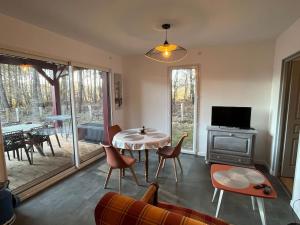 sala de estar con mesa, sillas y TV en Maison neuve à deux pas du Lac, en Sanguinet
