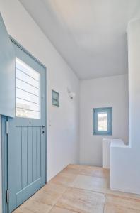 Habitación blanca con puerta azul y escalera en Villa Afroditi, en Antíparos
