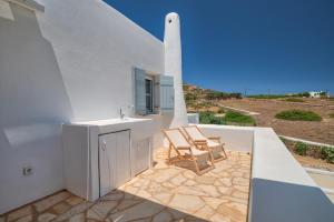 a white house with two chairs on a patio at Villa Afroditi in Antiparos