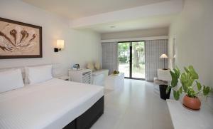 a white bedroom with a bed and a bathroom at EKHO Weligama in Weligama