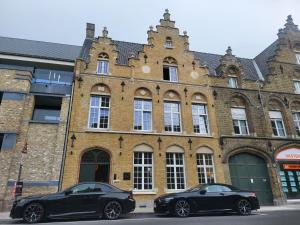 two black cars parked in front of a building at St-Georges IV in Ypres