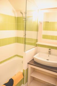 a bathroom with a tub and a sink and a shower at Résidence Goélia La Pommeraie in Branville