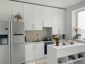 a white kitchen with white cabinets and a refrigerator at Стильна квартира студія у центрі міста in Luts'k