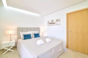 una camera bianca con un grande letto con cuscini blu di Casa Nico OceanView -Apartment 1901 a Portimão