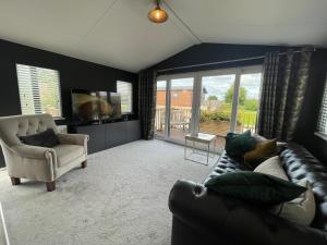 16 Lake View, Pendle View Holiday Park, Clitheroe في كليثروي: غرفة معيشة مع أريكة جلدية وكرسي