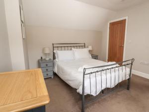 a bedroom with a bed with white sheets and a wooden table at Riverside Lodge in Alnmouth