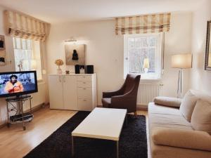 a living room with a couch and a tv at Appartmenthaus Sonnenburg in Kühlungsborn