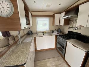 a small kitchen with a clock on the wall at Captivating 3-Bed Caravan at Golden Palm Skegness in Skegness