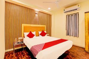 a hotel room with a large bed with red pillows at Hotel Alexa in Ahmedabad