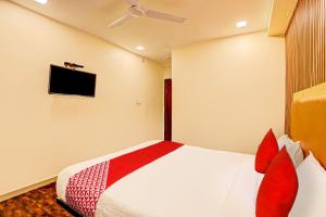 a bedroom with a bed with red pillows and a tv at Hotel Alexa in Ahmedabad