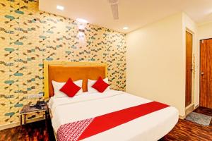 a bedroom with a large bed with red pillows at Hotel Alexa in Ahmedabad