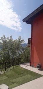 a red building with a bench next to a fence at Agriturismo Cascina Lert in Marone