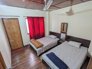 a room with two beds and a window with a red curtain at Mirabazar in Sylhet