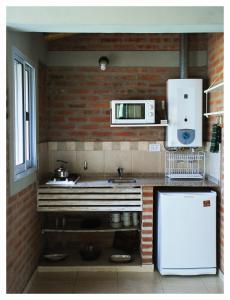 a kitchen with a sink and a microwave at Alma Serrana Apart Cabañas - Solo Adultos in Nono