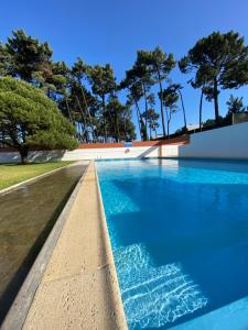a swimming pool with blue water and trees at CABEDELO BEACH FLAT in Viana do Castelo