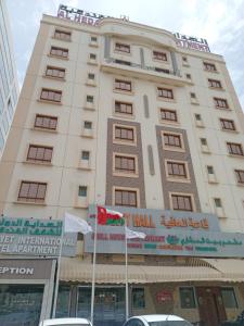 Al Hedayet International Hotel في سيب: مبنى طويل مع اثنين من الأعلام أمامه