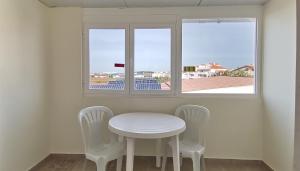 - une table et des chaises blanches dans une chambre avec fenêtre dans l'établissement Hotel Hebe Peniche, à Peniche