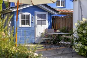 einem blauen Schuppen mit einem Tisch und Stühlen auf einer Terrasse in der Unterkunft Kamminke - Haffkieker in Kamminke