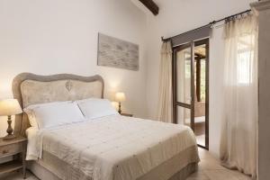 a white bedroom with a bed and a window at Relais Villa Carola in Porto Cervo