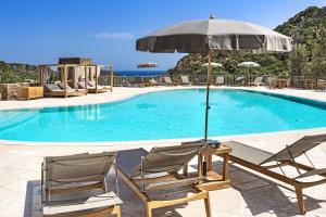 un paio di sedie e un ombrellone accanto alla piscina di Relais Villa Carola a Porto Cervo