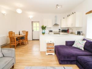 a living room with a purple couch and a kitchen at Whinstone in Keisley