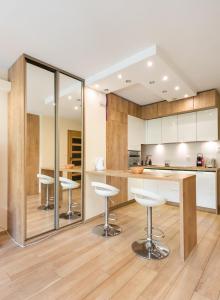 a kitchen with white cabinets and bar stools at Mokotów Orzycka Beige Studio in Warsaw