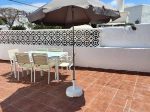 una mesa y sillas con una sombrilla en el patio en Casa El Eco del Volcán 1 en Teguise