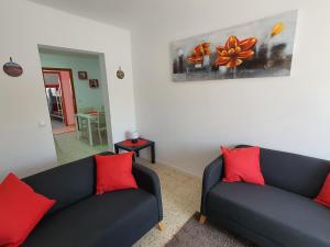 uma sala de estar com 2 sofás pretos e almofadas vermelhas em Casa El Eco del Volcán 1 em Teguise