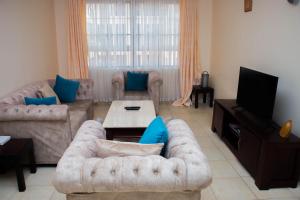 sala de estar con sofá y TV en Lux Suites Greatwall Getaway Apartments en Machakos