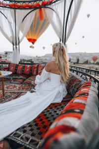Una donna con un vestito bianco seduta su un divano di Cappadocia View Suit a Göreme