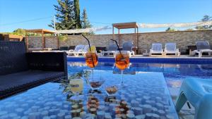 una mesa con gafas junto a una piscina en Hôtel Le Mas Des Amandiers en Graveson