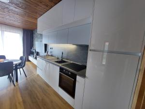 a kitchen with white cabinets and a sink and a table at Apartmán C2 Hrabušice in Hrabušice