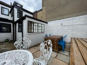 a patio with white chairs and a table and a wooden table at Pass the Keys Sea Haven Stylish Beach Oasis in Hastings
