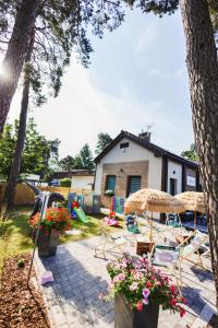 una casa y un patio con sillas y sombrilla en RABA RESORT - Domki i Apartamenty pod Krakowem, en Gdów