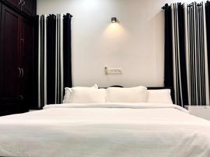 a bedroom with a white bed with black curtains at Garuda Suites in Varkala