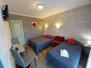 Habitación con 2 camas, escritorio y silla. en Hôtel L'Oustalet en Font Romeu Odeillo Via