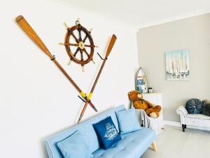 a living room with a blue couch and a steering wheel on the wall at Seafront Apartment in Portsmouth