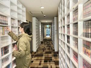 a woman is looking for a book in a library aisle at HOTEL StoRK in Naha +12 photos