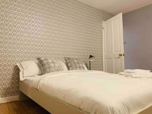 Schlafzimmer mit einem Bett mit weißer Bettwäsche und Tapeten in der Unterkunft 3 Bedrooms spacious house in Calcot , Reading in Tilehurst