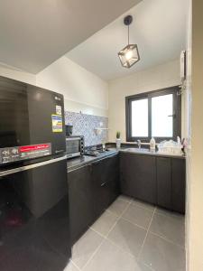 une grande cuisine avec des armoires noires et un micro-ondes dans l'établissement Madinaty Stylish furnished 1 bedroom Apartment-شقة فندقيه للايجار مدينتي, à Madinaty