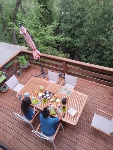 two people sitting at a table on a deck at Chambres d'hôtes Le Bois Des Frênes in Montarnaud