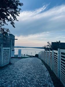 a cobblestone road with a fence next to the water at Sobe Djurdjevic in Zatonje