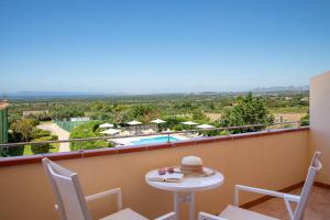 a balcony with a table and chairs and a pool at Lu' Hotel Porto Pino in SantʼAnna Arresi