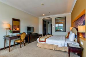 um quarto de hotel com uma cama, uma secretária e uma televisão em La Sapinette Hotel Dalat em Da Lat