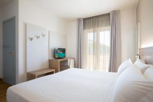 a bedroom with a white bed and a window at Lu' Hotel Porto Pino in SantʼAnna Arresi